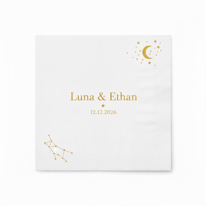 May include: A square white paper napkin featuring gold foil accents. The design includes a crescent moon and stars in the top right corner, a constellation in the bottom left, and the text Luna & Ethan with the date 12.12.2026 in the center.