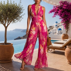 May include: A sleeveless, pleated jumpsuit in a vibrant magenta hue featuring a bold yellow and white floral pattern. The garment includes a deep V-neckline with a central gold-toned zip closure, a fitted waist, and wide-leg trousers.