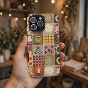 Puede incluir: Una funda para smartphone con una cuadrícula de ilustraciones cuadradas que incluyen una taza de café, una tetera, un gato durmiendo, una vela, un tulipán, un patrón de cuadros, tartán, manzanas, pájaros y calcetines en tonos tierra.
