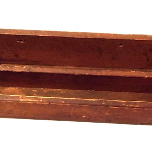 May include: A rectangular, open-top wooden box with a dark brown finish. The box has a central divider and two small holes near the top edge. The wood shows signs of wear, suggesting age and use. Ideal for storage.