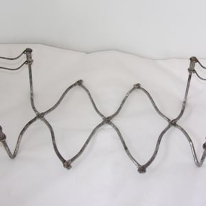 May include: An antique, metal, expandable pot rack with a distressed, silver finish. The rack features a zig-zag design in the centre and curved end pieces. It is designed to hang from the ceiling.