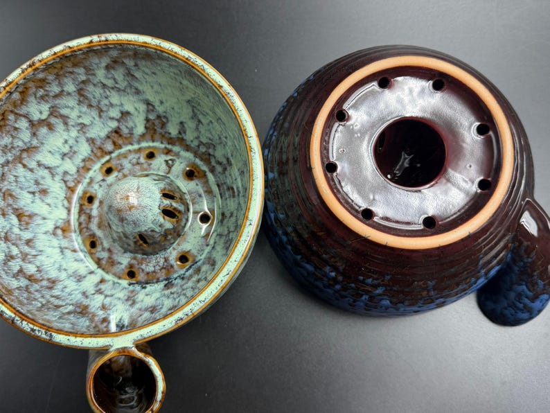 May include: A ceramic coffee dripper shown from two angles. The left side displays the interior with a light blue and brown mottled glaze and a central drainage cone. The right side shows the dark brown and blue exterior base with drainage holes.