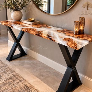 May include: A console table featuring a live-edge wood slab with white resin inlay, supported by a black metal X-frame base. The surface holds a round vase, a small bowl, and two cylindrical candle holders. The logo reads LUKE HANDICRAFT STORE.