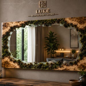 May include: A rectangular wall mirror featuring a live edge wood frame with natural wood grain and embedded green moss. The mirror has an irregular, organic-shaped reflective center. Above the mirror, the text LUKE HANDICRAFT STORE is displayed.