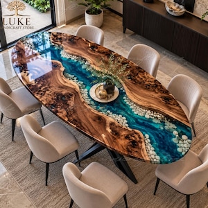 Puede incluir: Una mesa de comedor ovalada con dos grandes losas de madera natural de borde irregular, separadas por una incrustación central de resina azul translúcida rellena de piedras de río blancas, sobre una base de metal negro con seis sillas beige.