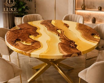 Puede incluir: Una mesa de comedor redonda que presenta una losa de madera natural con bordes orgánicos y una incrustación de resina amarilla translúcida y lisa que fluye por el centro. La mesa se apoya sobre una base de metal dorado con patas cruzadas.