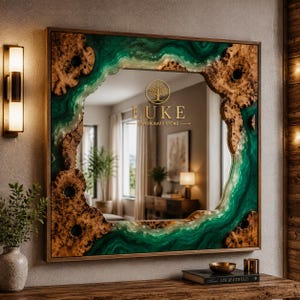 Könnte beinhalten: Ein quadratischer Wandspiegel mit einem Rahmen aus natürlichem Wurzelholz und durchscheinendem smaragdgrünem Harz. In der Mitte des Spiegels befindet sich der goldene Schriftzug LUKE HANDICRAFT STORE mit einem Baum-Symbol.