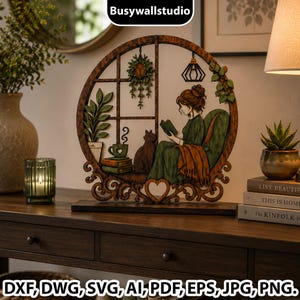 May include: A circular wooden wall art piece featuring a layered cutout design of a person reading a book in a green armchair next to a cat, a potted plant, and a window. The base includes a heart cutout. Text at the bottom reads DXF, DWG, SVG, AI, PDF, EPS, JPG, PNG.