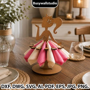 Puede incluir: Un servilletero de madera marrón con forma de silueta de persona con coleta, que presenta un diseño de falda acampanada que sostiene servilletas alternas de color rosa y crema. La figura tiene un pequeño detalle floral en el pelo y el pecho.