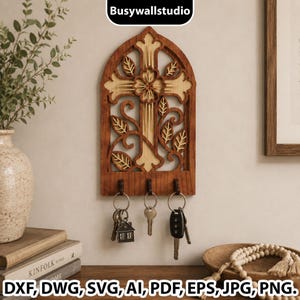 May include: A wall-mounted wooden key holder featuring an arched frame with a cutout cross and floral design. The piece has three dark hooks at the bottom, each holding a set of keys. The wood displays a two-tone finish with light and dark brown sections.