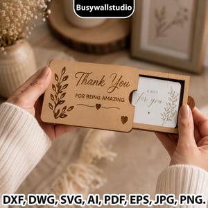 Puede incluir: Una caja deslizante rectangular de madera con el texto grabado a láser Thank You FOR BEING AMAZING junto a una rama de hojas y corazones. Dentro, una tarjeta blanca muestra el texto A GIFT for you con una rama y un corazón a juego.