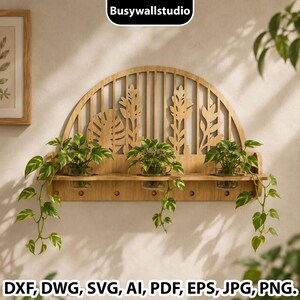 Puede incluir: Un estante de pared de madera semicircular con un diseño botánico cortado con láser, listones verticales y motivos de hojas. El estante sostiene tres frascos de vidrio transparente, cada uno con una planta potos verde con enredaderas. Texto: Busywallstudio.