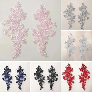 Può includere: Una collezione di paia di applicazioni in pizzo floreale in vari colori, tra cui rosa chiaro, argento, blu scuro, nero e rosso. Ogni applicazione presenta un intricato disegno botanico ricamato con steli, foglie e piccoli fiori a spirale.