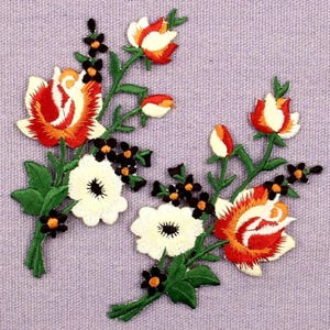 Puede incluir: Dos parches florales bordados que presentan grandes rosas naranjas y blancas, flores blancas más pequeñas y diminutas flores negras con centros naranjas. Los diseños incluyen tallos y hojas verdes con un bordado detallado.