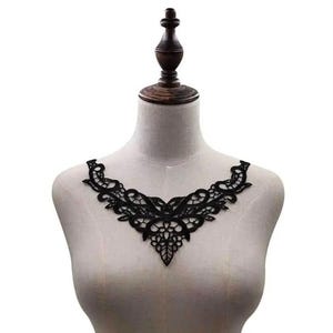 Peut inclure: Une application de col en dentelle noire présentant un motif floral et végétal complexe avec un design en forme de V pointu. La broderie délicate met en valeur des détails ajourés et des bords festonnés pour orner les vêtements.