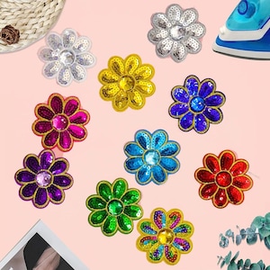 May include: A collection of ten flower-shaped patches featuring sequins and a central faceted gem. The patches come in various colors including silver, yellow, blue, purple, magenta, green, red, and a multi-colored option with gold trim.