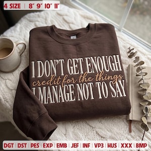 May include: A dark brown crewneck sweatshirt featuring embroidered text that reads I DON'T GET ENOUGH credit for the things I MANAGE NOT TO SAY. The text is in white and light brown, with 4 sizes listed as 8, 9, 10, and 11 inches.