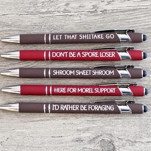May include: Five retractable ballpoint pens with stylus tips, featuring brown and red barrels. Each pen displays white text: LET THAT SHIITAKE GO, DON'T BE A SPORE LOSER, SHROOM SWEET SHROOM, HERE FOR MOREL SUPPORT, and I'D RATHER BE FORAGING.
