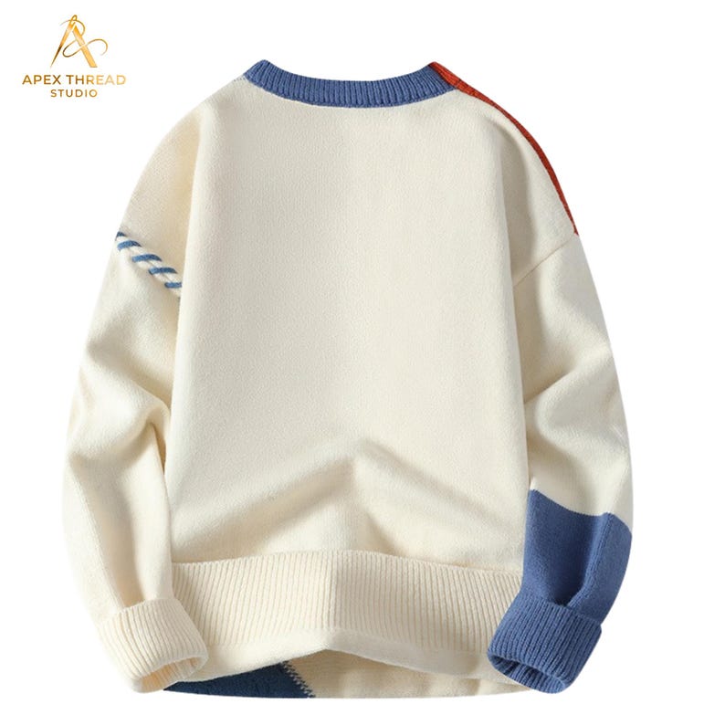 May include: A cream-colored long-sleeve knit sweater featuring a blue ribbed crew neckline, cuffs, and hem. The sweater includes color-blocked accents in blue and red on the shoulders and lower sections, with a blue and white striped detail on one sleeve.
