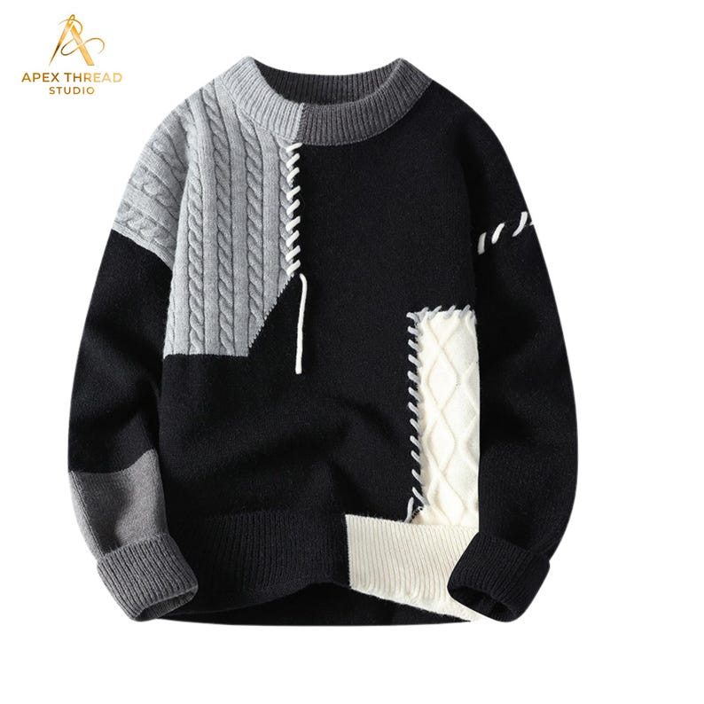 May include: A long-sleeve crewneck sweater featuring a color-blocked design in black, gray, and white. The garment includes a gray cable-knit panel on the upper right, a white cable-knit panel on the lower right, and white whipstitch detailing.