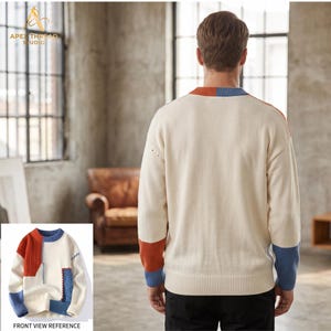 May include: A long-sleeve crewneck sweater in off-white featuring color-blocked panels in burnt orange and blue. The design includes a ribbed collar, cuffs, and hem, with a textured knit pattern on the front panels and a solid back panel.
