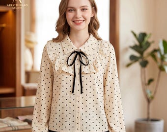 Blusa color crema con volantes y lunares, lazo negro y top coqueto de manga larga.