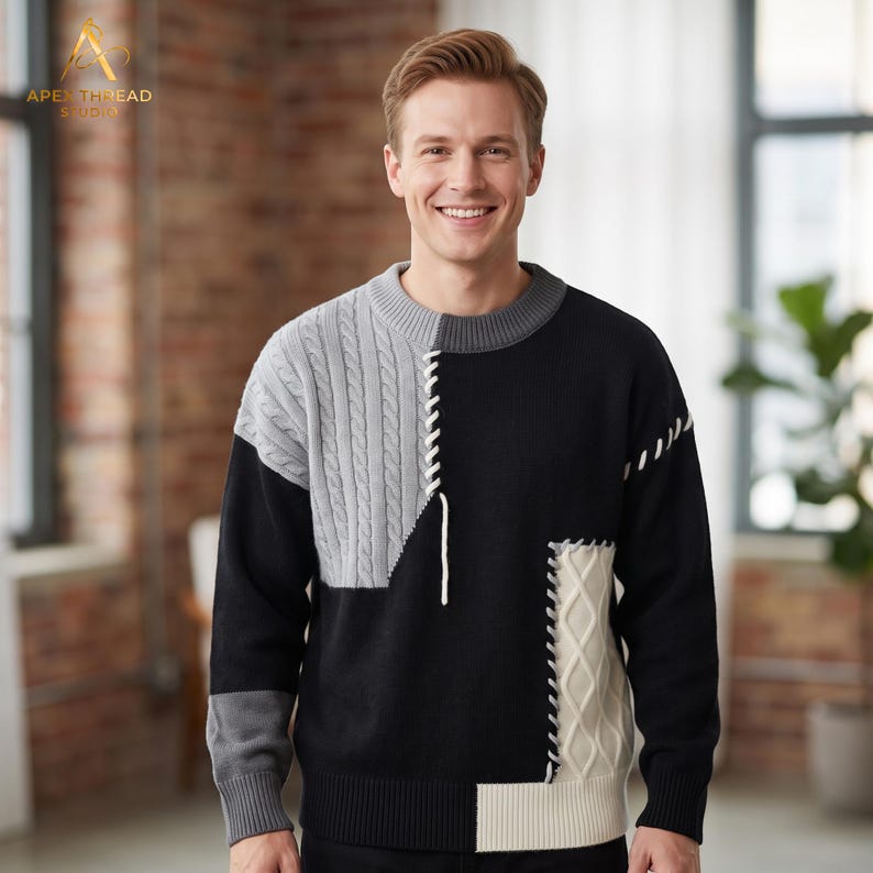 May include: A long-sleeve crewneck sweater featuring a color-blocked design in black, light gray, and cream. The garment incorporates cable-knit panels on the upper right and lower left, accented by white decorative lacing details along the seams.