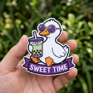 May include: An embroidered patch featuring a white duck with an orange beak and feet, wearing purple round sunglasses. The duck holds a cup of green bubble tea with a straw. Below the duck is a purple banner with the white text SWEET TIME.