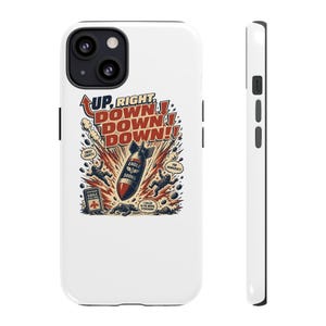 May include: A white smartphone case featuring a graphic illustration of a falling bomb labeled EAGLE 500KG, surrounded by figures in tactical gear, explosions, and text that reads UP, RIGHT, DOWN, DOWN, DOWN, SWEET LIBERTY, FOR DEMOCRACY, and EAGLE.