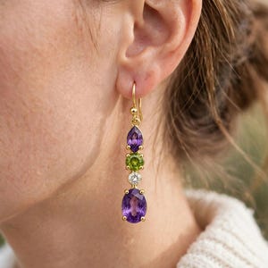 Könnte beinhalten: Ein goldener Ohrhänger mit einem violetten Amethyst im Marquise-Schliff, einem grünen Peridot im Rundschliff, einem kleinen runden klaren weißen Diamanten und einem großen ovalen violetten Amethyst, gefasst in Goldkrallen.