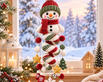 May include: A crocheted snowman hanging decoration featuring a red and green hat, a matching scarf, and a spiral body in red, green, and white. The ornament includes dangling crocheted stars, small trees, red mittens with white snowflakes, and a silver bell.