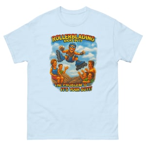 May include: Pale blue t-shirt with a vibrant graphic of a rollerblader in action, accompanied by the text "ROLLERBLADING KICKS BUTT" and "THE PROBLEM IS... IT'S YOUR BUTT!". The design includes cartoon figures and a sky background.