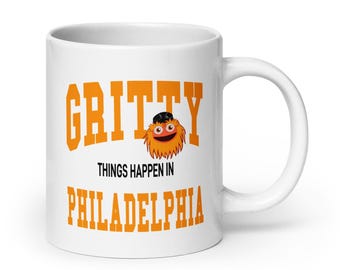 May include: White ceramic mug with an orange and black cartoon mascot with the text "Gritty Things Happen in Philadelphia" printed on it.