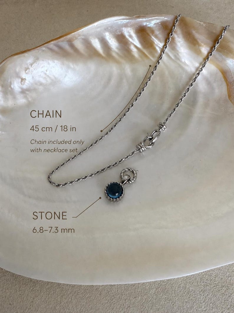 Pode incluir: Um colar de corrente torcida prateada com 45 cm de comprimento e um pendente circular com uma pedra azul-escura de 6,8&ndash;7,3 mm. A corrente inclui um fecho decorativo e &eacute; apresentada com um pendente a condizer neste conjunto.