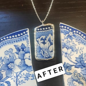 May include: A rectangular pendant necklace with a silver chain. The pendant features a blue and white floral pattern, framed in silver. The necklace is displayed with broken pieces of a matching blue and white patterned plate. The word "AFTER" is visible.