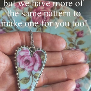 May include: A silver heart-shaped pendant necklace with a floral pattern on a blue background. The pendant is surrounded by a silver beaded border. The text "SET SOLD to June of Granby, Canada but we have more of the same pattern to make one for you too!" is visible in the image.