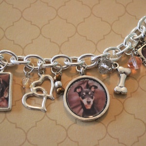 May include: A silver charm bracelet with multiple charms, including two dog photos, a heart, a bone, and a crystal charm.
