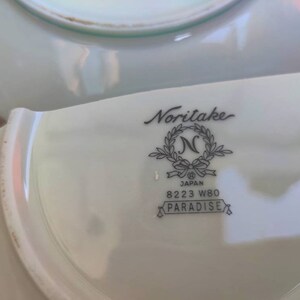 May include: A white porcelain saucer with a Noritake Japan logo and the words "8223 W80 Paradise".