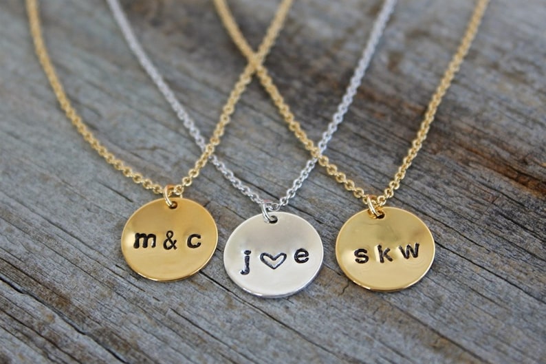 May include: Three gold necklaces with round pendants. The pendants are engraved with the initials "m&c", "j&hearts;e", and "skw".