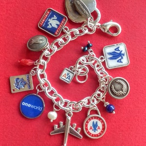 Puede incluir: Un brazalete de plata con varios dijes, incluyendo un coraz&oacute;n, un avi&oacute;n y varios dijes con el logotipo de American Airlines. Los dijes est&aacute;n en una cadena de plata con un cierre de langosta.