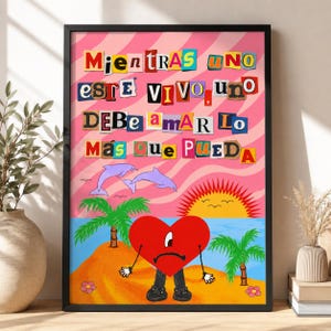 Op de afbeelding: Een ingelijste poster met tekst in collage-stijl die luidt: "MIENTRAS UNO ESTE VIVO, UNO DEBE AMAR LO MAS QUE PUEDA". Het kunstwerk toont een rood hart-personage met een verdrietig gezicht, twee palmbomen, twee dolfijnen en een zon op een strand.