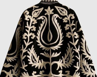 May include: A black jacket featuring long sleeves and a high collar, adorned with intricate white embroidery in a symmetrical floral and leaf pattern that covers the entire back and extends across the sleeves and the collar area.