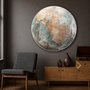 May include: A large circular wall art piece featuring a textured, relief-style surface that resembles a planetary landscape. The artwork displays a mix of muted blue, earthy brown, and cream tones with a raised, cratered, and uneven finish.