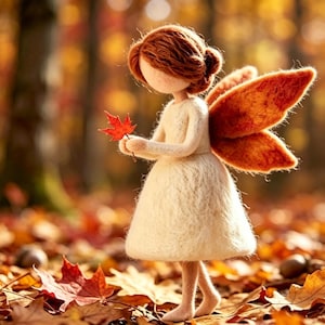 May include: A needle-felted doll with auburn hair, wearing a cream-colored dress and large orange wings. The doll holds a small, vibrant red maple leaf in its hands, standing upright with a soft, textured appearance against a blurred autumn forest.