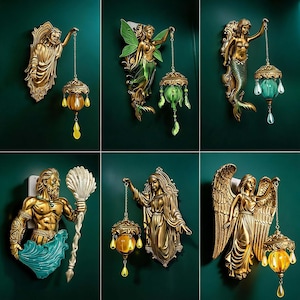 Può includere: Una collezione di sei applique decorative da parete con figure scolpite in tonalità oro, tra cui una figura barbuta, una fata con ali verdi, una sirena, una figura muscolosa con un tridente, una figura drappeggiata e un angelo.