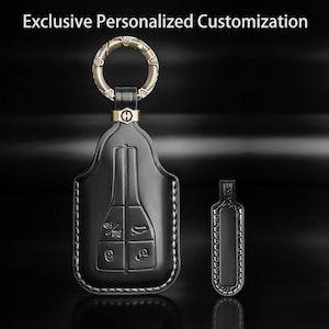 Könnte beinhalten: Eine schwarze Autoschlüsselhülle aus Leder mit weißen Nähten, einem Metallring und einem kleinen rechteckigen Anhänger. Der Text Exclusive Personalized Customization ist oben sichtbar. Die Hülle hat geprägte Tasten-Symbole für Fahrzeugfunktionen.