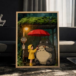 Könnte beinhalten: Ein gerahmter Kunstdruck, der ein großes graues Wesen und ein Kind im gelben Regenmantel unter einem roten Regenschirm an einer Bushaltestelle zeigt. Die Szene umfasst ein bemoostes Dach, Regen, eine leuchtende Straßenlaterne und ein Schild mit dem Text BUB.