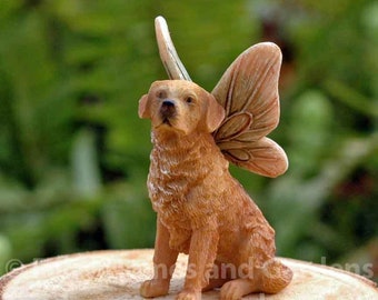 May include: A golden retriever figurine with a delicate butterfly wing design. The figurine is sitting on a wooden surface and has a realistic, detailed appearance.