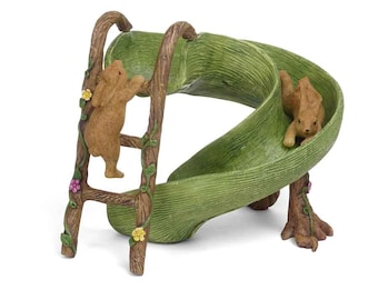 May include: A green and brown wooden slide and ladder with two brown rabbits, one climbing the ladder and the other going down the slide.