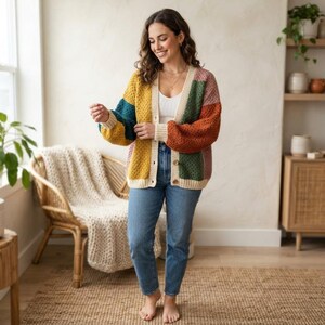 Può includere: Un cardigan in maglia a blocchi di colore con abbottonatura e polsini color crema. Il capo presenta pannelli in giallo senape, verde ottanio, arancione ruggine e rosa antico con una lavorazione all'uncinetto, indossato sopra una canotta bianca e jeans.